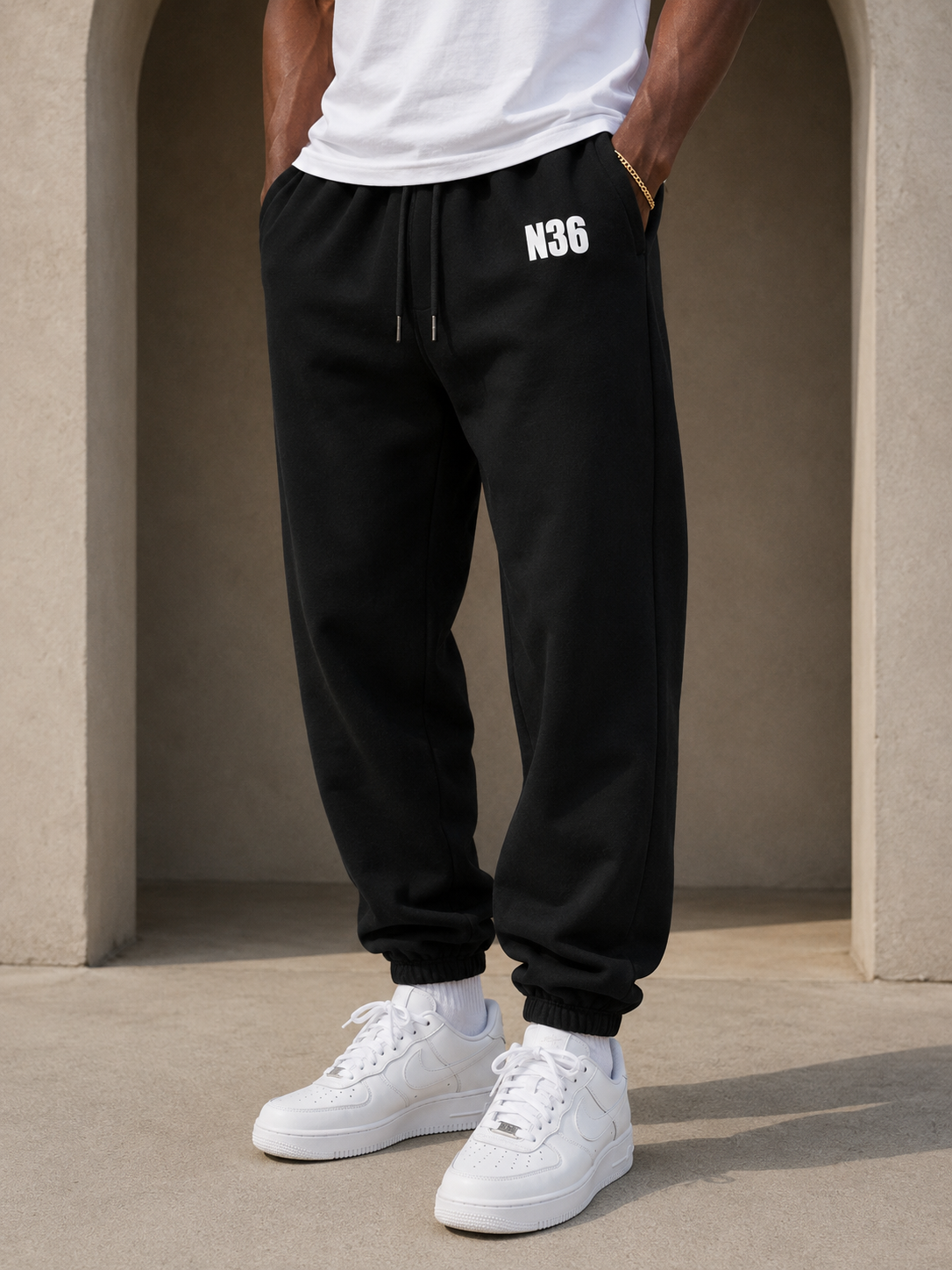 Man wearing N36 unisex black trackpants with white thigh logo, elastic waistband and drawstring